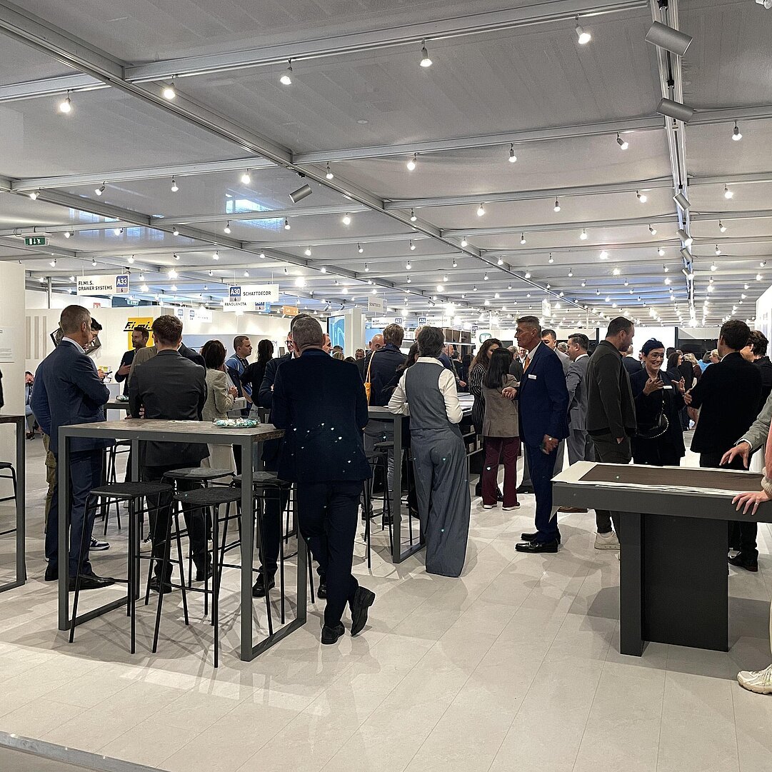 Besucher im Gespräch am Schattdecor-Stand der SICAM 2026, links das Dekor Calacatta Viola im Großformat-Digitaldruck