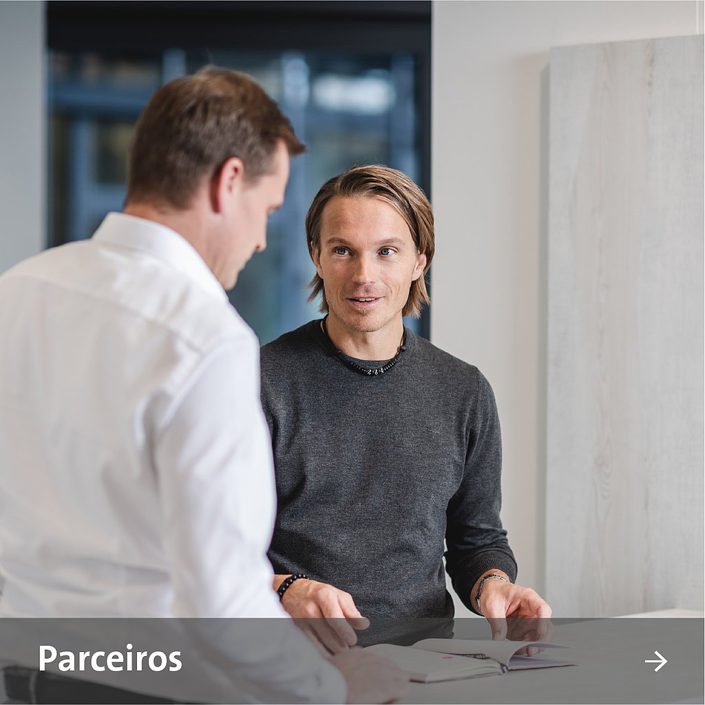Dois colegas estão de pé um ao lado do outro e conversam