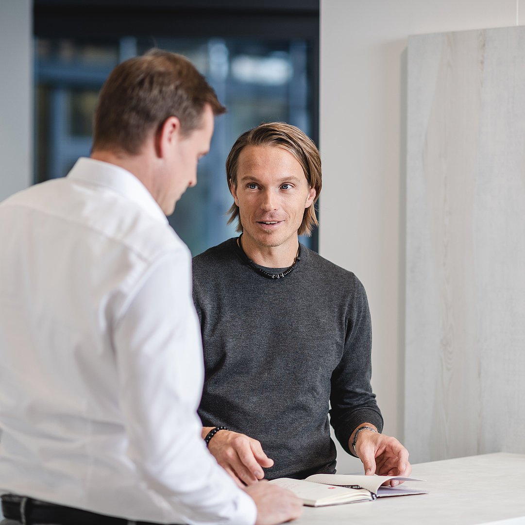 Two colleagues are standing next to each other and talking.